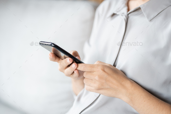 Hands of young woman in casual shirt or blouse holding smartphone