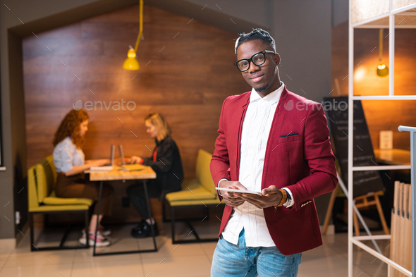 Young elegant man of African ethnicity in smart casualwear using digital tablet - Stock Photo - Images