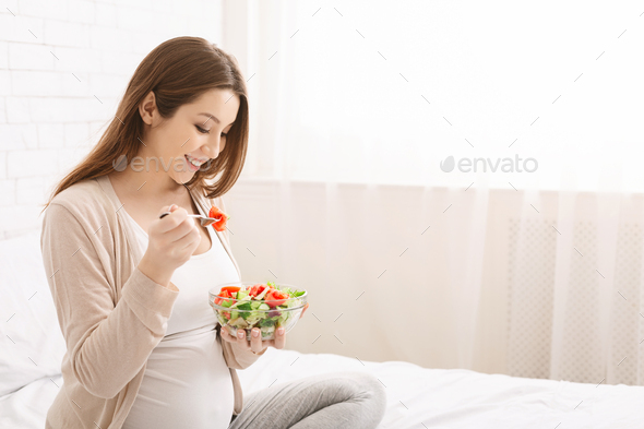 Pregnant millennial woman eating natural vegetable salad