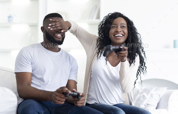 Millennial couple playing videogames sitting on couch at home - Stock Photo - Images