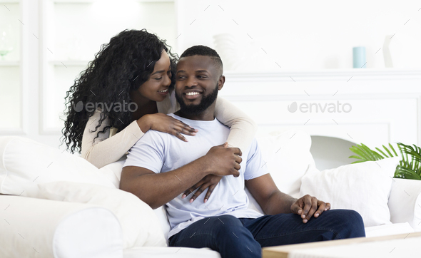 Playful african american woman whispering something to her boyfriend\'s ear