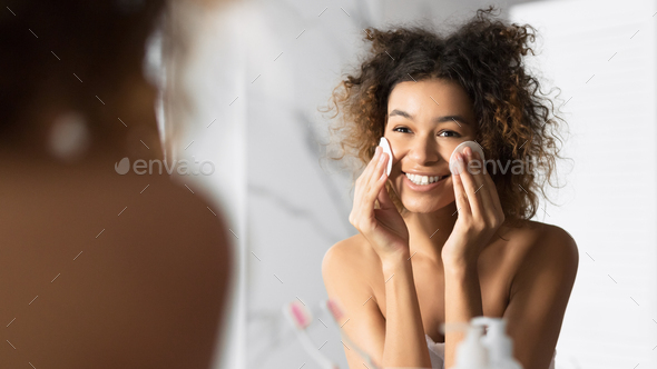 African American Girl Holding Cotton Pads Cleaning Face In Bathroom - Stock Photo - Images