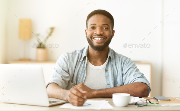 Happy african american freelancer sitting at workplace in home office
