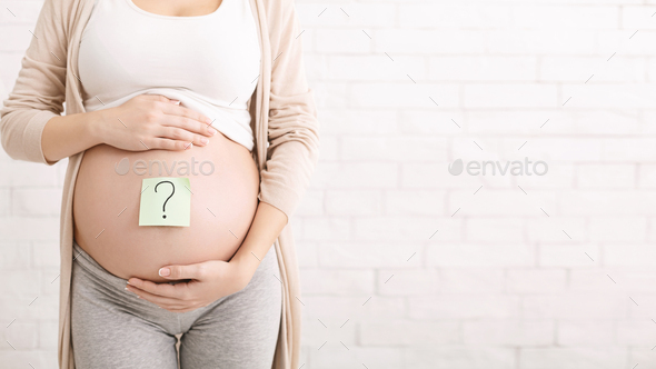 Pregnant woman embracing her belly with question mark on it - Stock Photo - Images