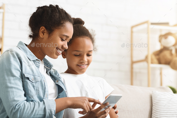 African sisters checking on new mobile application at home