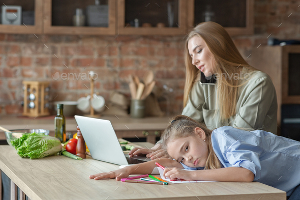 Upset little girl feeling bored while mom working from home