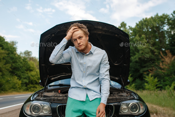 Tired young man at the opened hood, car breakdown - Stock Photo - Images