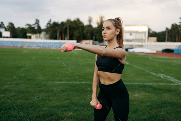 Female runner in sportswear holds dumbbells - Stock Photo - Images
