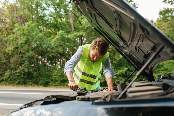 Man in reflective vest at opened hood, breakdown