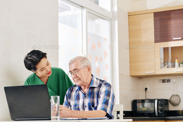 Caregiver helping senior man with computing - Stock Photo - Images