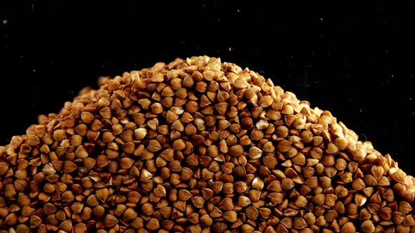 Buckwheat groats are poured on a black background. alt