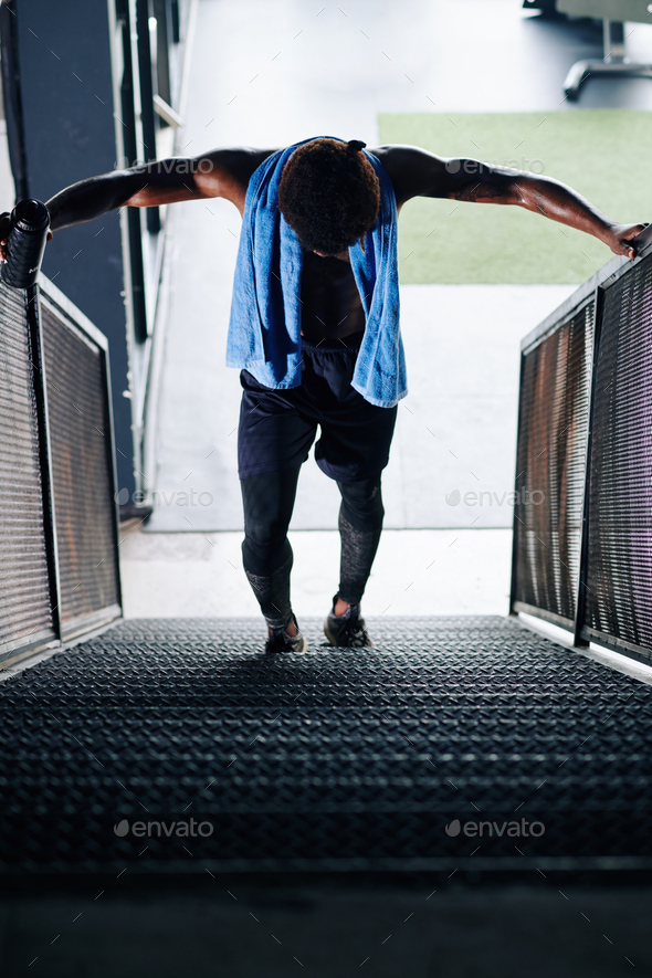 Sportsman struggling walking up the stairs after leg day