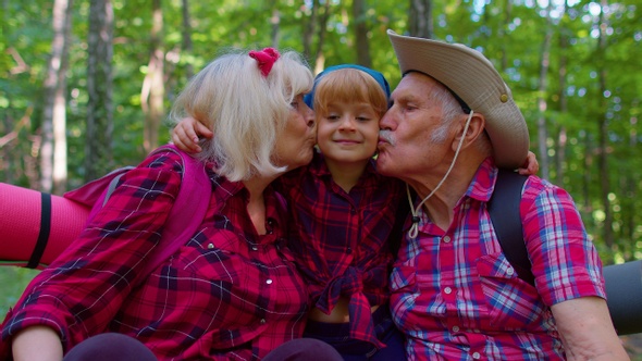 Active Senior Grandmother Grandfather Tourists Sitting Hiking with Granddaughter in Summer Wood alt