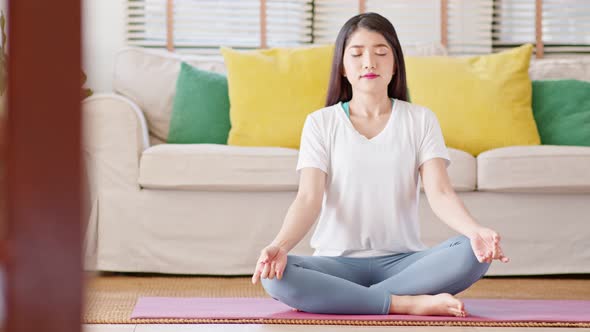Asian young woman sit on carpet breathing with yoga lotus pose alt