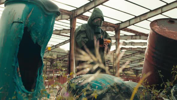 Man with Geiger Counter Near Radioactive Barrels alt