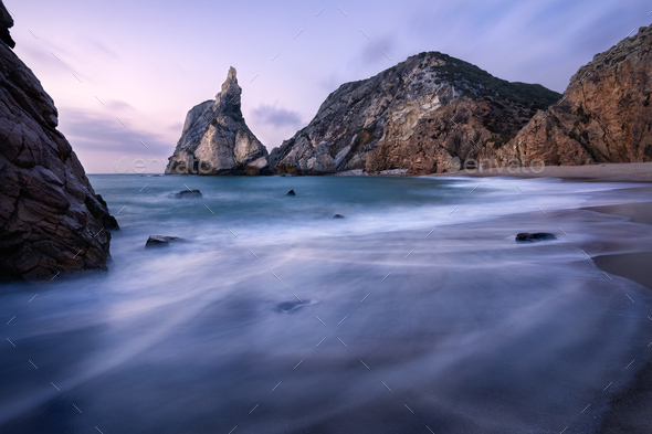 Epic Ursa Beach, Sintra, Portugal. Beach with waves and jugged rock peak in evening soft sunset - Stock Photo - Images