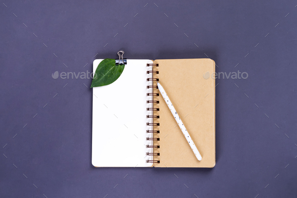 Mockup blank paper notebook and green leaf on a gray background
