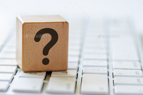 Small wooden dice with question mark on keyboard