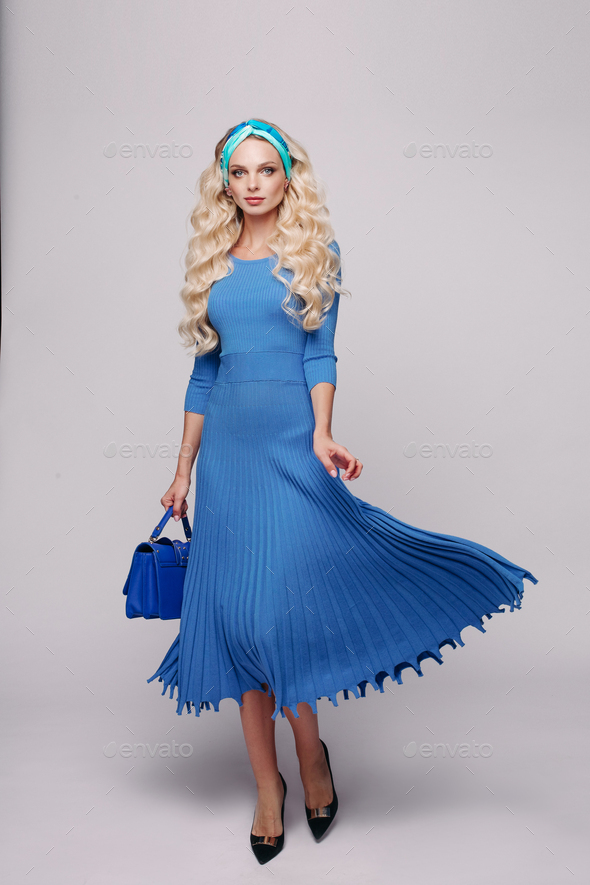Glamour elegance young blonde woman in blue dress holding small bag at white studio background - Stock Photo - Images
