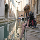 Caucasian redhead woman with floral dress sitting near a canal in Venice barefoot - PhotoDune Item for Sale