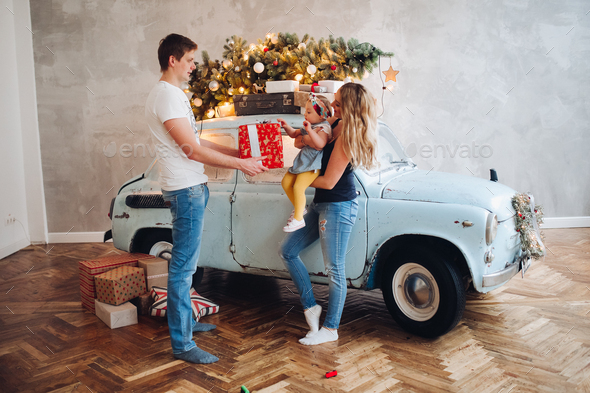 Lovely daddy giving Christmas present, big red box, for blonde mom and little cute daughter - Stock Photo - Images
