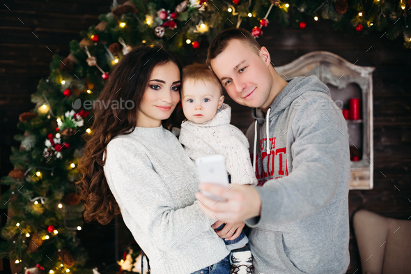 Happy family with adorable kid having fun at Christmas tree - Stock Photo - Images