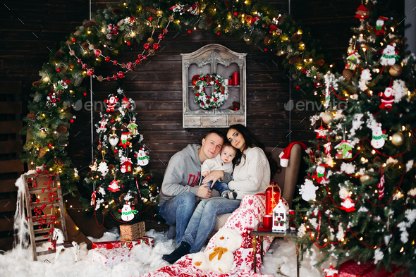 Happy family with adorable kid having fun at Christmas tree - Stock Photo - Images