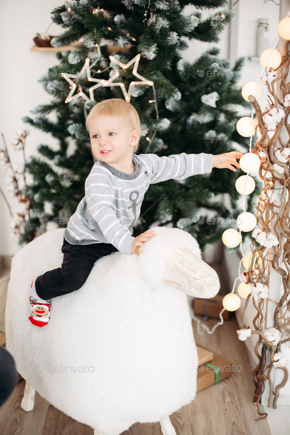 Blonde little boy in gray sweater and black jeans lying on roof among confetti - Stock Photo - Images