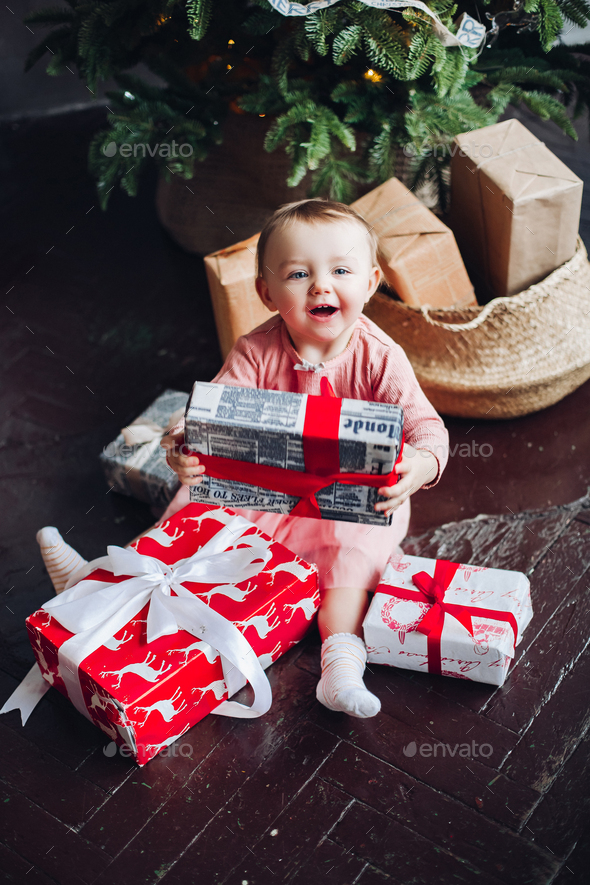 Portrait of happy little girl sitting on roof in decorated studio and playing with Christmas - Stock Photo - Images