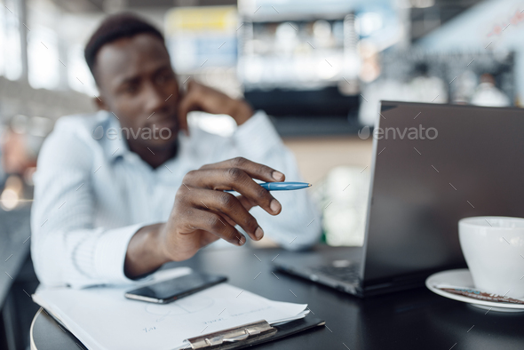 Ebony businessman working on laptop in office cafe