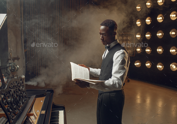 Ebony pianist with music notebook on the stage