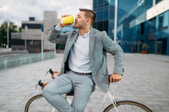 Businessman with bike drinks coffee in downtown