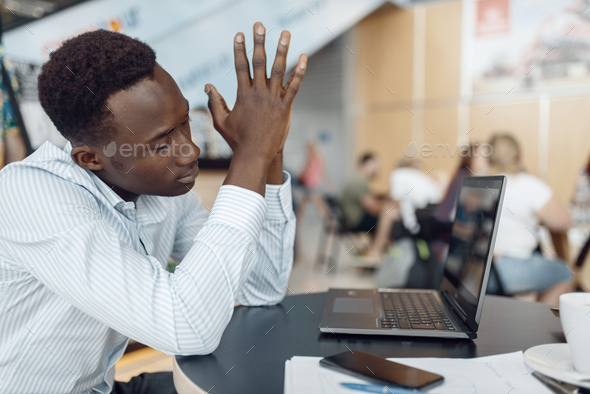 Ebony businessman working on laptop in office cafe