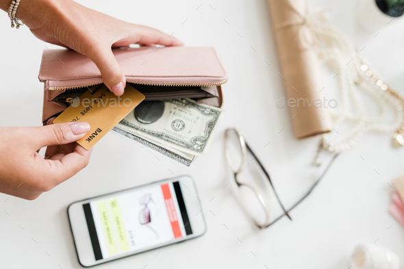 Hands of young woman holding leather wallet with dollar bills and plastic card - Stock Photo - Images