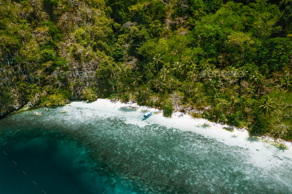 Aerial drone view of a secluded deserted tropical beach with lonely tourist boat surrounded by - Stock Photo - Images
