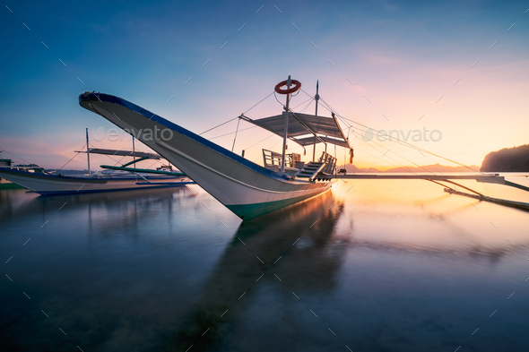 El Nido, Palawan, Philippines. Traditional banca boat in the beach bay in golden sunset light - Stock Photo - Images