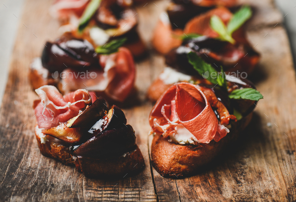 Crostini with prosciutto, goat cheese and grilled figs on board - Stock Photo - Images