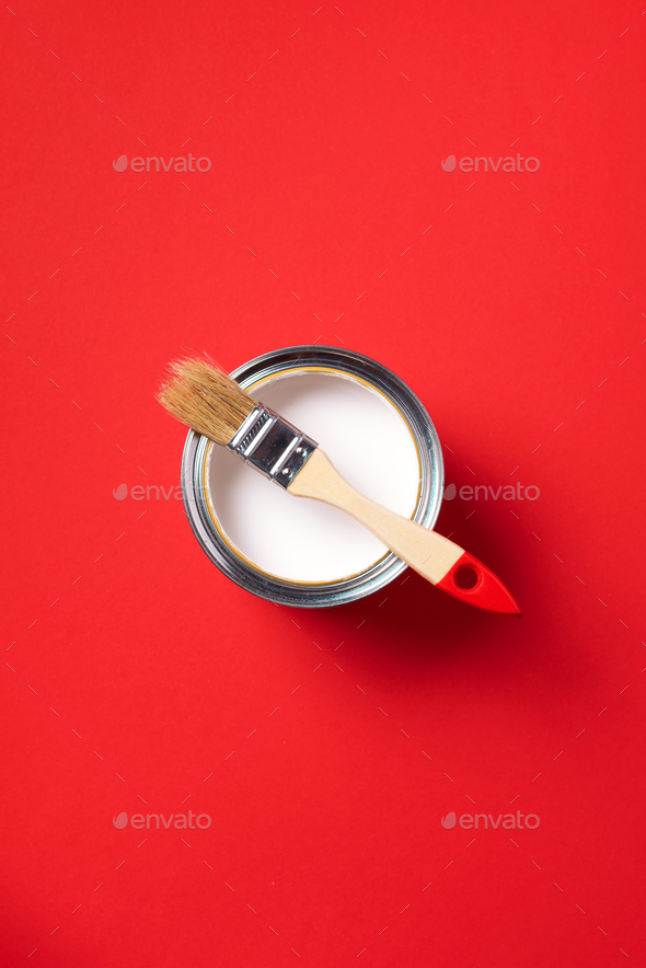 Brush and open paint can on trendy red background. Top view, copy space. Appartment renovation - Stock Photo - Images