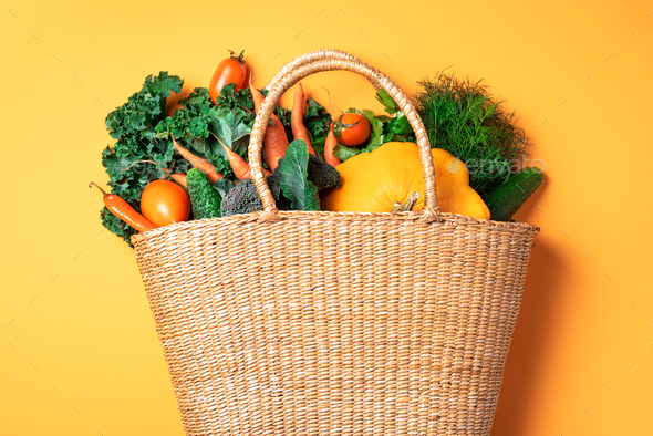 Straw basket with organic vegetables over trendy yellow background. Healthy food, vegetarian diet - Stock Photo - Images