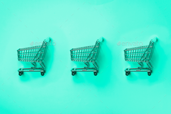 Shopping cart on mint color background. Minimalism style. Creative design. Shop trolley at