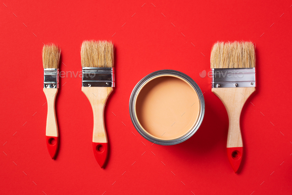Brush and open paint can on trendy red background. Top view, copy space. Appartment renovation - Stock Photo - Images
