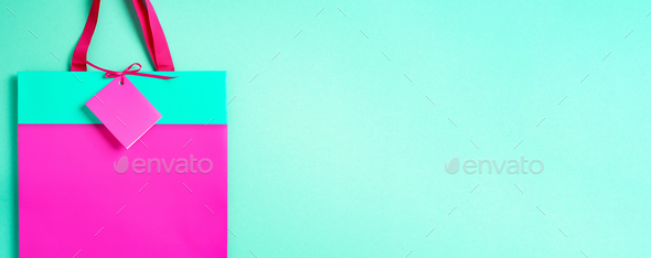 Top view of turquoise and pink paper shopping bag on trendy green background. Copy space. Gift - Stock Photo - Images
