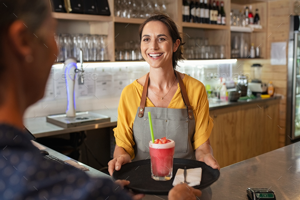 Smiling waitress serving strawberry smoothie - Stock Photo - Images