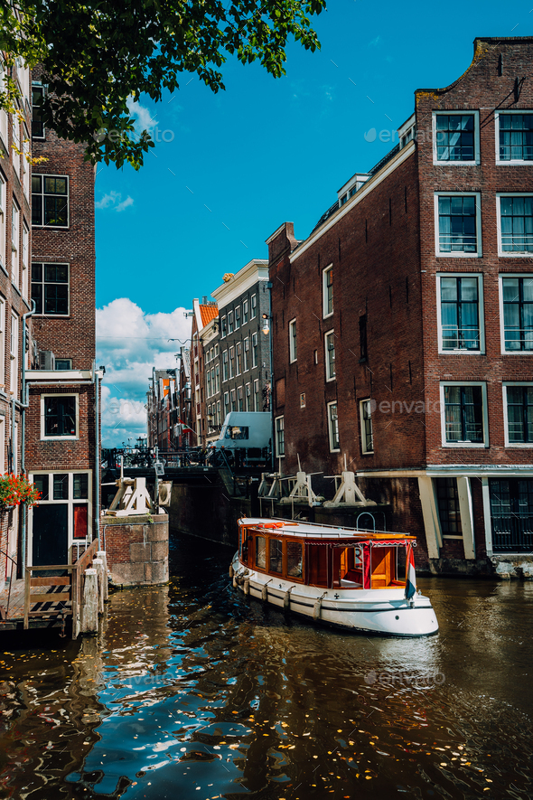 Small Tourist boat floating picturesque dutch channel passing traditional brick houses. Colorful - Stock Photo - Images