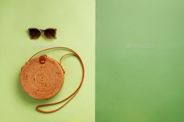 Round rattan bag, sunglasses on green background. Banner. Top view with copy space. Trendy bamboo - Stock Photo - Images