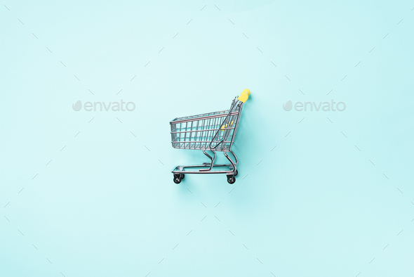 Shopping cart on blue background. Minimalism style. Creative design. Top view with copy space. Shop