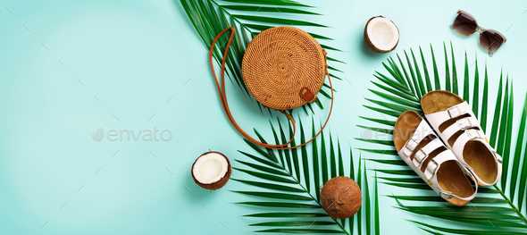 Round rattan bag, coconut, birkenstocks, palm branches, sunglasses on blue background. Banner. Top - Stock Photo - Images