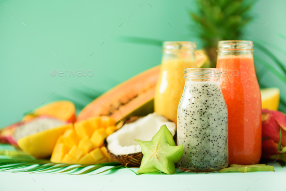 Papaya, dragon fruit, pineapple, mango smoothie in jars on turquoise background. Detox, vegan diet - Stock Photo - Images