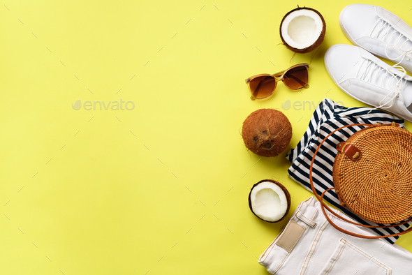 Female white sneakers, jeans, striped t-shirt, rattan bag, coconut and sunglasses on yellow - Stock Photo - Images
