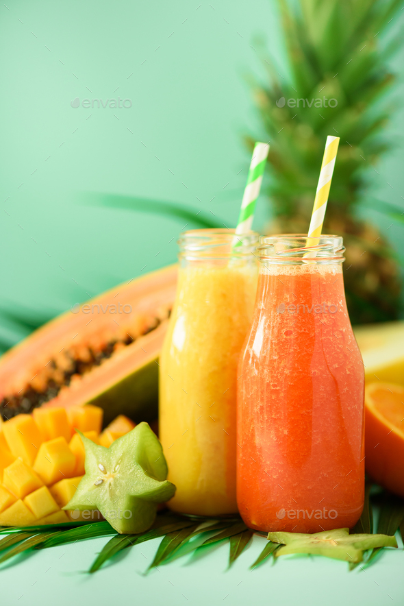 Juicy papaya and pineapple, mango, orange fruit smoothie in two jars on turquoise background. Detox - Stock Photo - Images